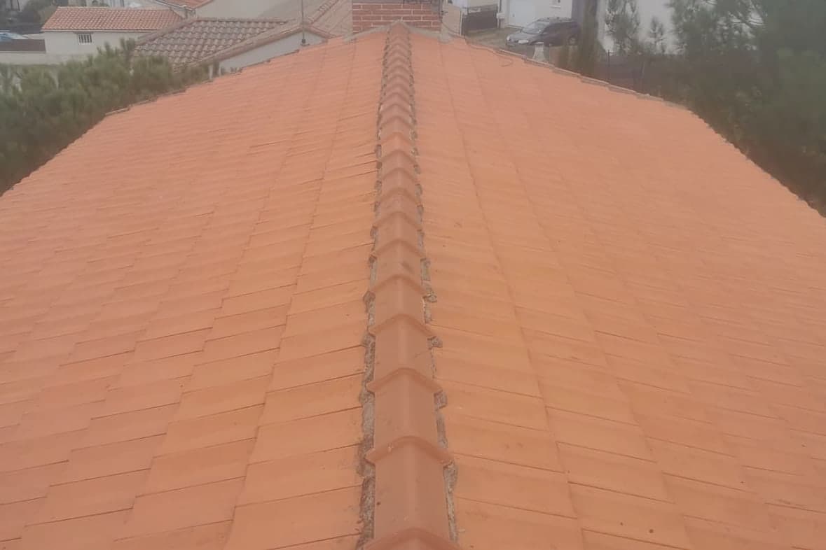 Toiture en tuiles à la teinte orange uniforme après travaux, faîtage repris dans la même teinte