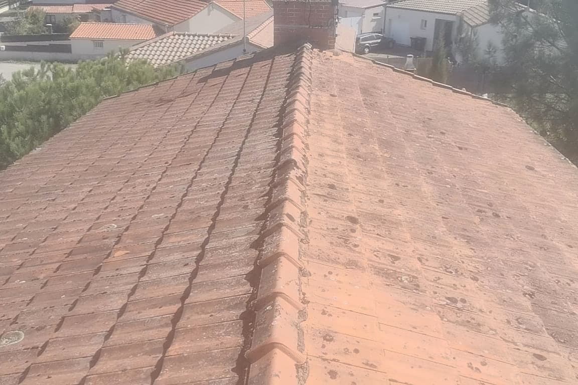 Toiture en tuiles mécaniques délavées et tachées de lichens avant travaux, vue prise depuis le faîtage